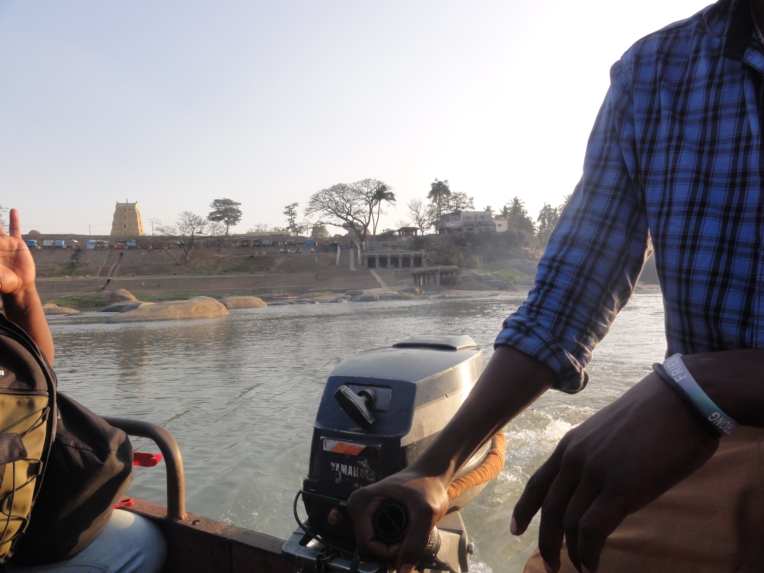 the engine of the motor boat and half of the guy who is driving it. We are on the water, half way across, heading to the north side of the river. 